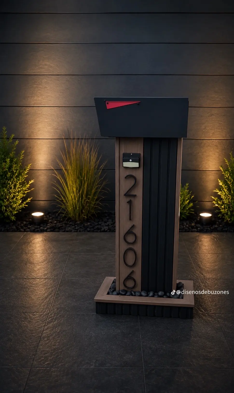 Black mailbox with red flag on a narrow pedestal with a light wood-look face, vertical black address numbers and a small light